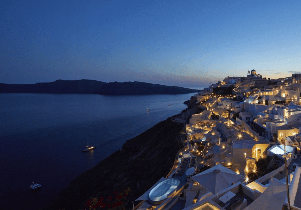 Scenic night view from the hilltop at Erossea Villa Santorini, featuring a starry sky and distant lights in the landscape.