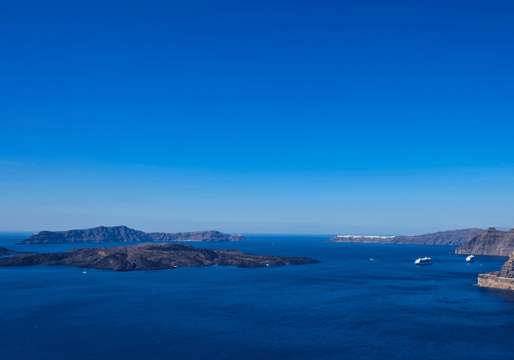 A bright blue sky featuring a few clouds, capturing the beauty of Santorini's landscape