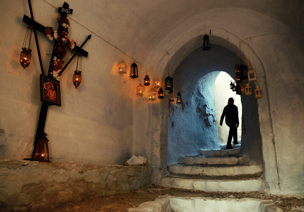 A man walks down a hallway adorned with a cross, capturing the essence of Greek Easter in Santorini
