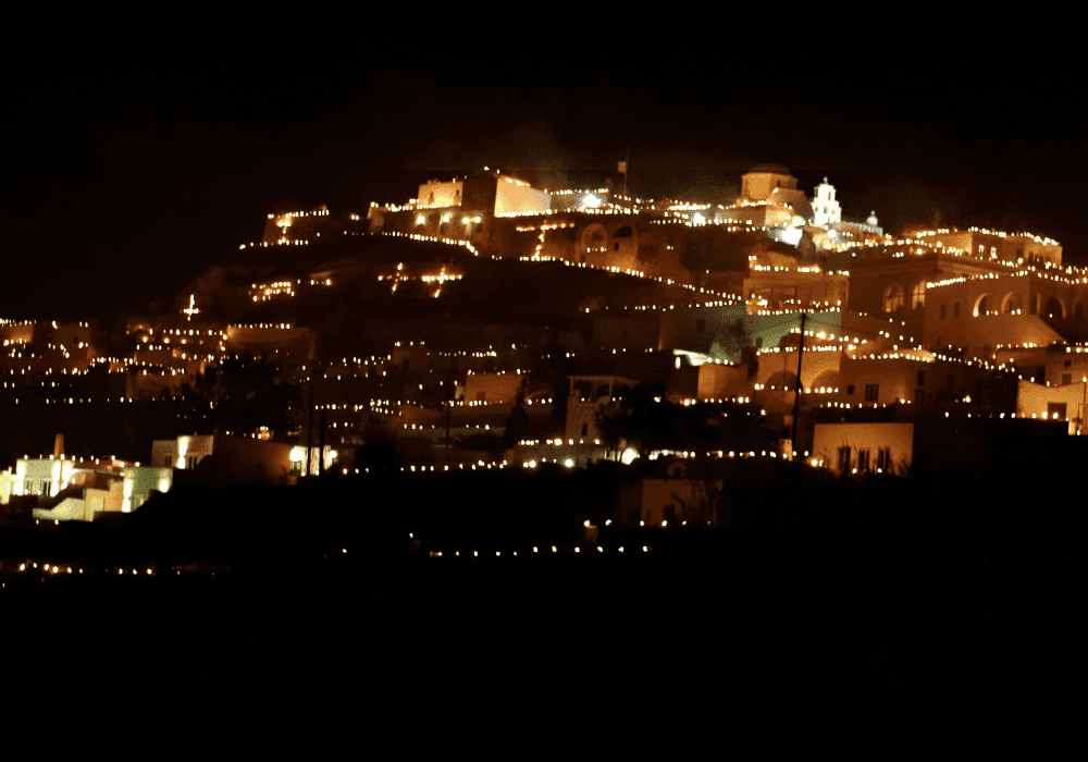 A picturesque city illuminated by candles at night, showcasing Erossea Villa during Greek Easter in Santorini
