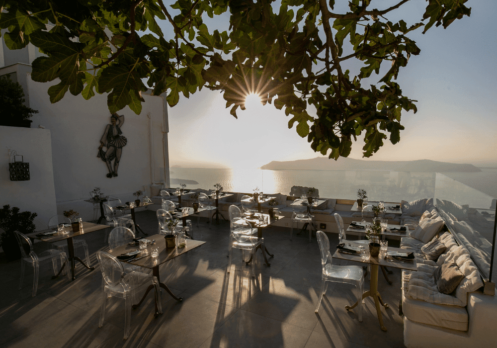 Scenic ocean view from a restaurant in Imerovigli, Santorini, adorned with tables and chairs for dining