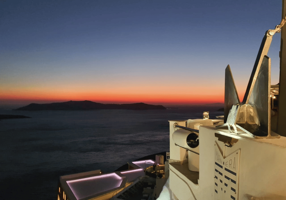 A breathtaking sunset over the sea and mountains in Oia, Santorini, casting vibrant colors across the sky